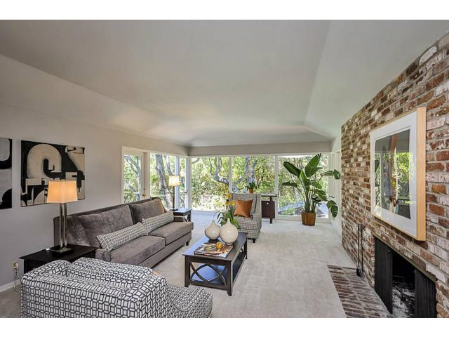 spacious and elegant living room with views of mature trees, grassy lawn and pool