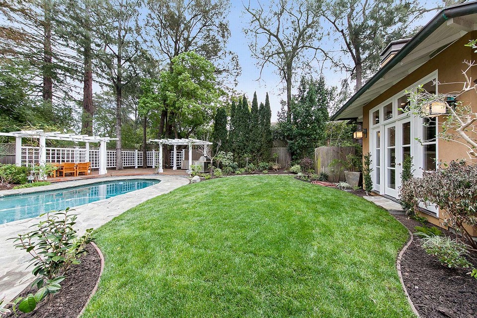 private and lush rear gardens with mature trees, grassy play space and outdoor kitchen