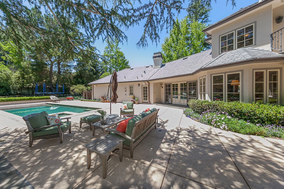 half acre yard includes a sparkling pool, entertainment deck, grassy play space and raised vegetable beds
